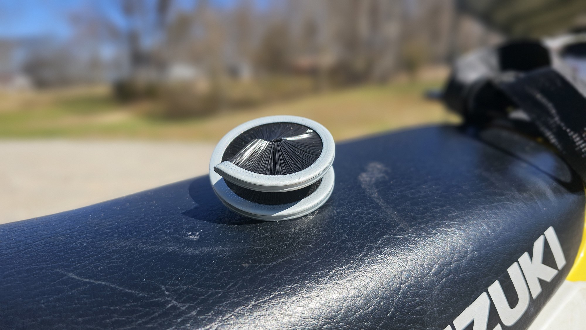 CC360 chain cleaning brush sitting on a Suzuki motorcycle seat
